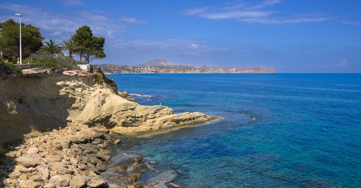 Beautiful coastal scene in Calpe, Spain with clear blue waters and rocky cliffs.